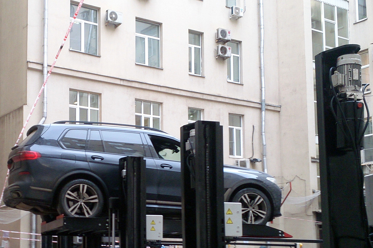 Автомобиль на верхнем уровне парковочного подъёмника во дворе социального департамента Правительства Москвы